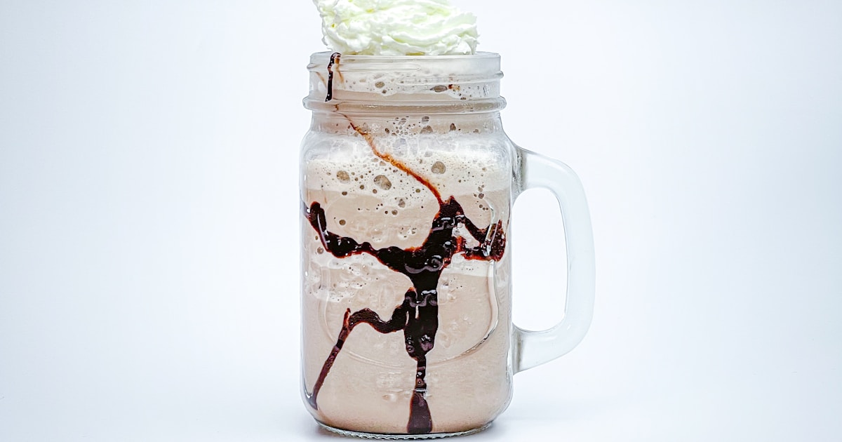 Smoothie protéiné dans un verre avec une banane et des flocons d'avoine en arrière-plan