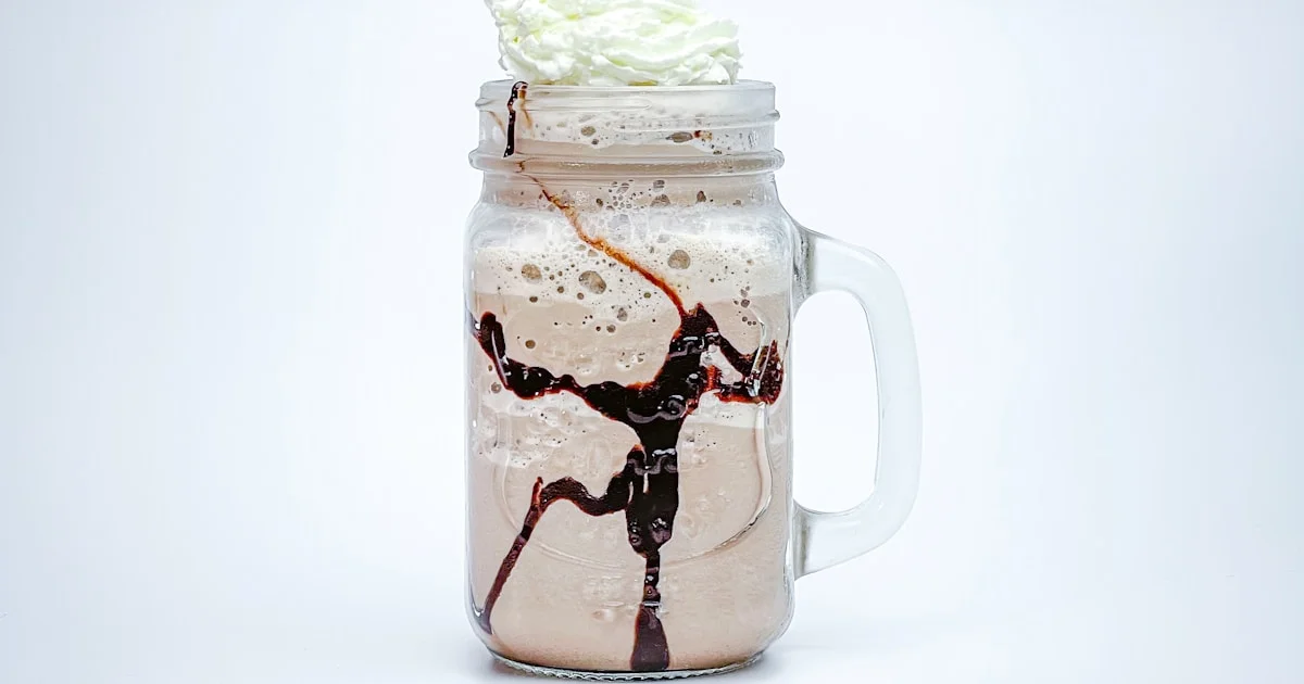Smoothie protéiné dans un verre avec une banane et des flocons d'avoine en arrière-plan